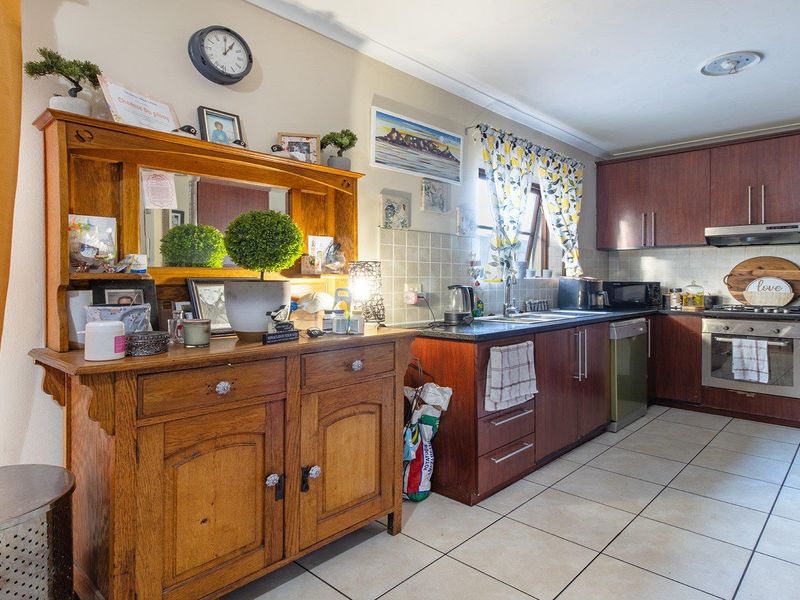 A functional kitchen featuring dark wood cabinetry, tiled flooring, a built-in oven, and an extractor fan, offering a practical layout for daily meal preparation.
