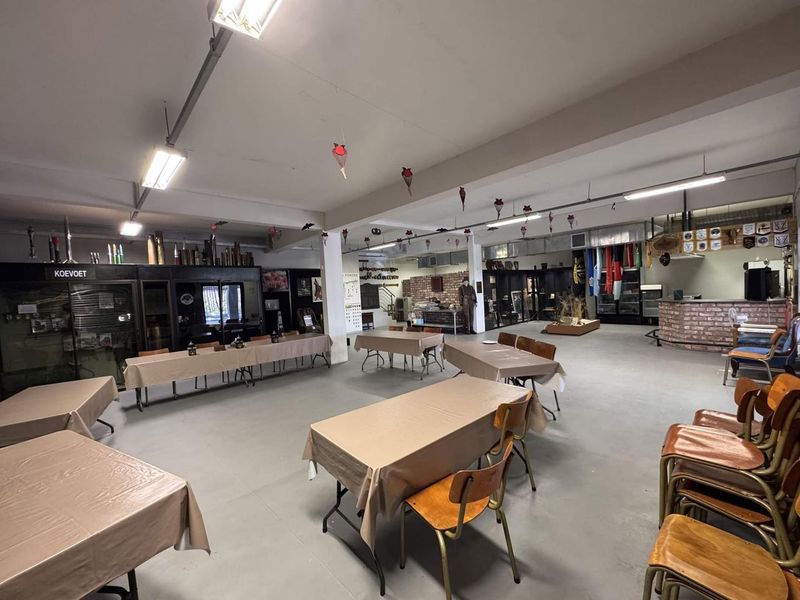Spacious clubhouse area featuring exposed ceiling beams, concrete flooring, a brick bar counter, and built-in display cabinets suitable for events or social gatherings.