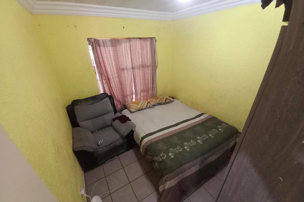 A compact bedroom featuring tiled flooring, yellow textured walls, and crown molding, providing a functional sleeping space.