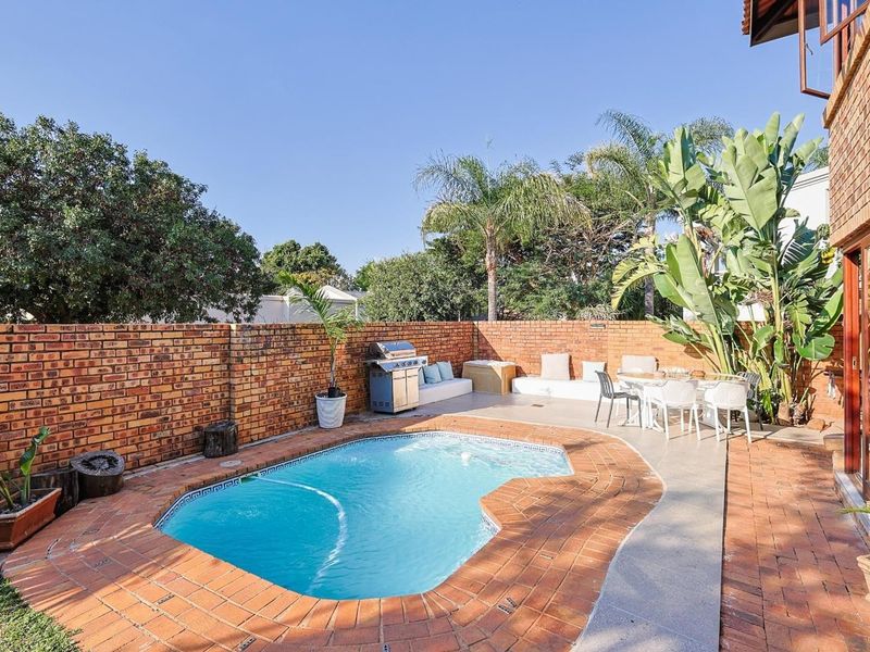 Private outdoor pool area featuring a swimming pool, brick paving, and a perimeter brick wall, ideal for outdoor relaxation and entertainment.