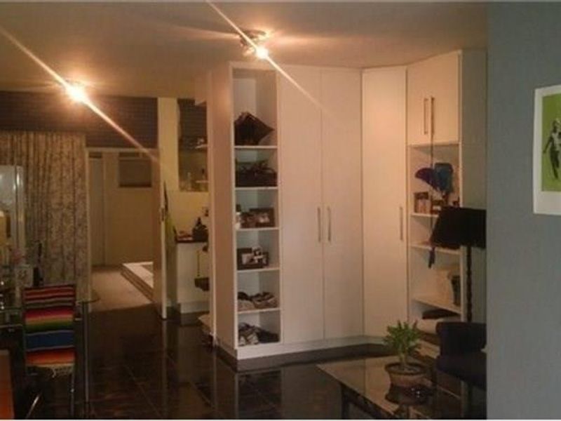 Open plan living area featuring extensive built-in white cabinetry and dark tiled flooring, providing ample storage and a modern layout.