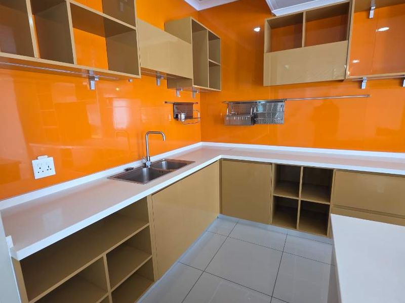 A modern, empty kitchen featuring vibrant orange cabinetry, white countertops, stainless steel sink, and tiled flooring with recessed ceiling lighting.