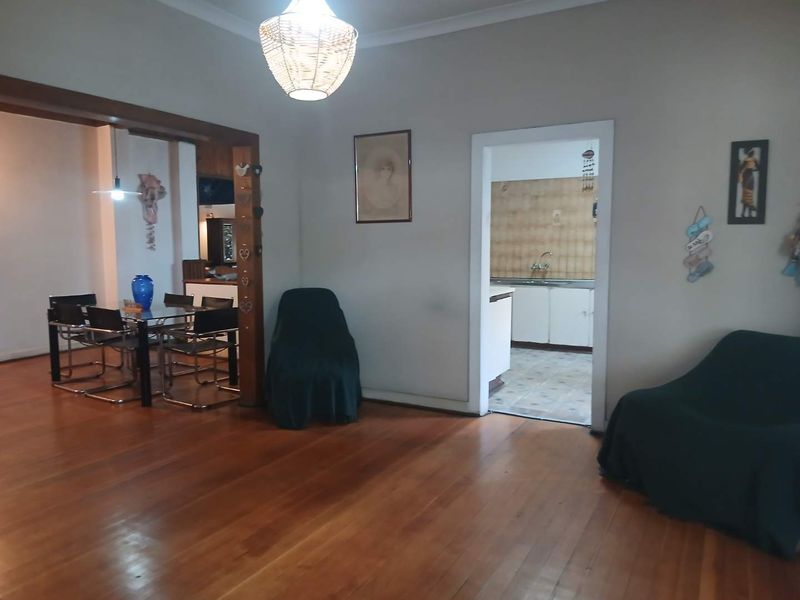 Open plan living and dining area featuring polished hardwood floors, with a view through to a functional kitchen space.