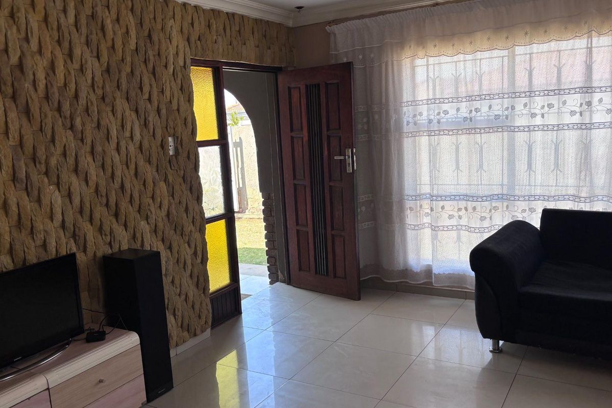 Living room featuring a textured stone accent wall, tiled flooring, and direct access to the exterior through a timber door.