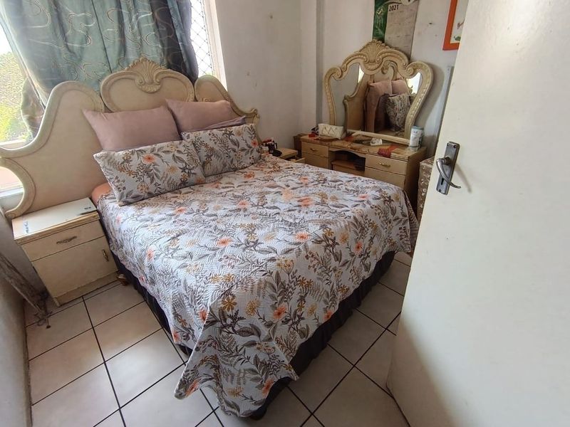 A bedroom featuring tiled flooring and a window with security bars, requiring cosmetic updates to improve the overall aesthetic and condition.