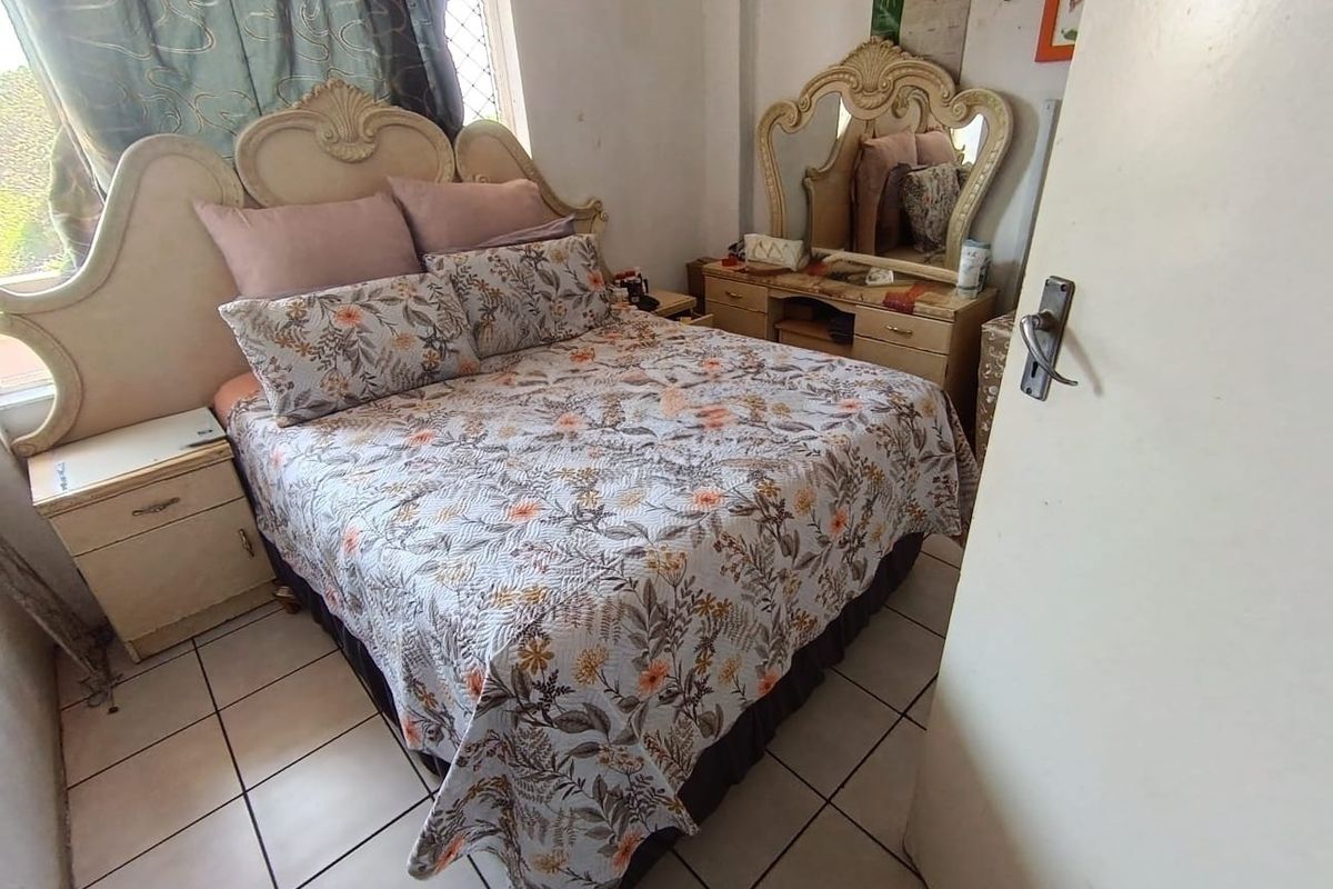 A bedroom featuring tiled flooring and a window with security bars, requiring cosmetic updates to improve the overall aesthetic and condition.