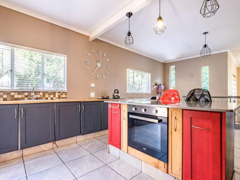 Modern kitchen featuring a central island with built-in oven, dark grey cabinetry, tiled backsplash, and tiled flooring with ample natural light.