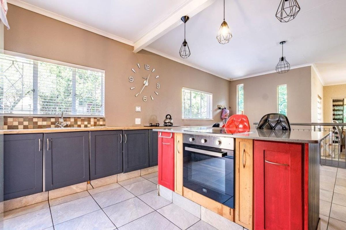 Modern kitchen featuring a central island with built-in oven, dark grey cabinetry, tiled backsplash, and tiled flooring with ample natural light.