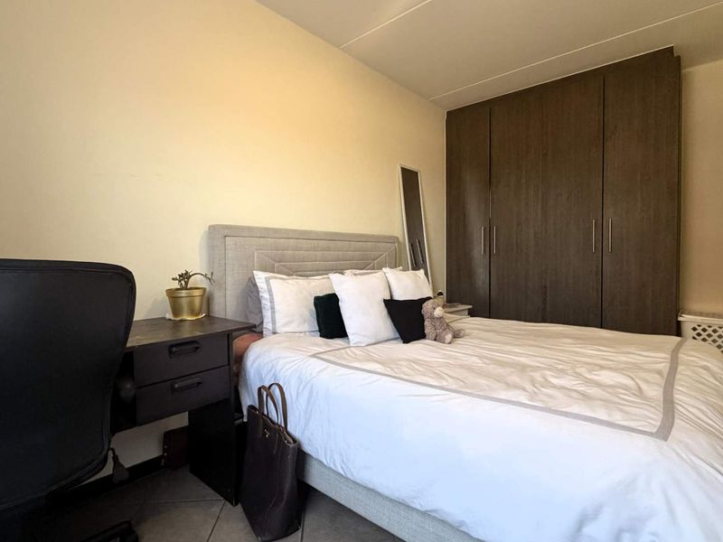 A functional bedroom featuring built-in wooden cupboards and tiled flooring, providing practical storage and a neutral foundation.