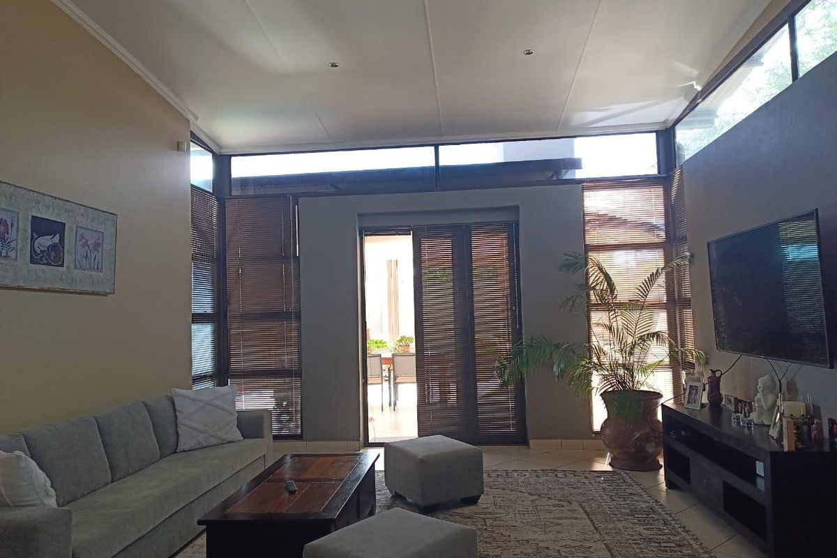 Spacious living room featuring high ceilings, clerestory windows, and large sliding doors providing seamless access to the outdoor patio area.