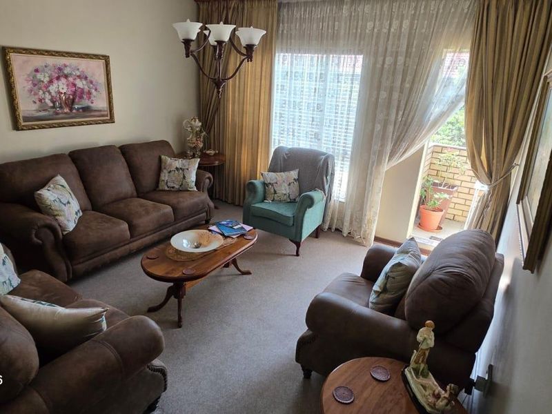 A comfortable living room featuring carpeted flooring and a sliding glass door that provides access to a small balcony.
