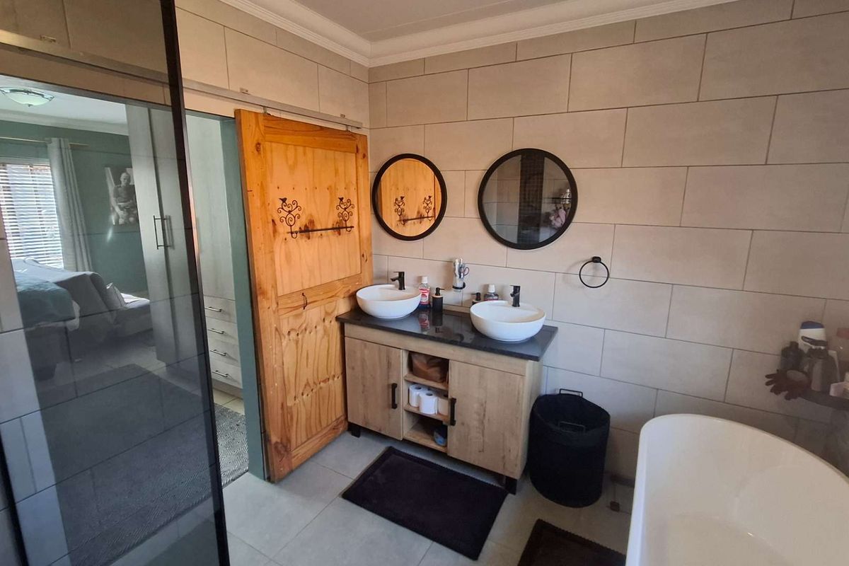 Modern bathroom featuring a double vanity with vessel sinks, a freestanding bathtub, a glass-enclosed shower, and a rustic sliding barn door.