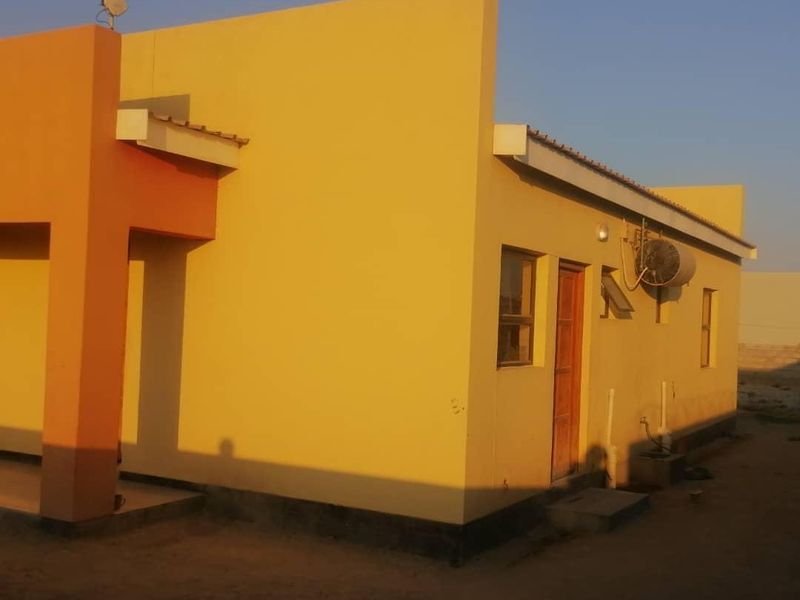 A side view of the property featuring plastered walls, an external air conditioning unit, and basic exterior lighting.