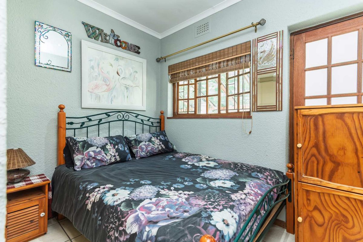 A cozy bedroom featuring tiled flooring, a timber-framed window, and a classic timber door, offering a functional and well-maintained living space.