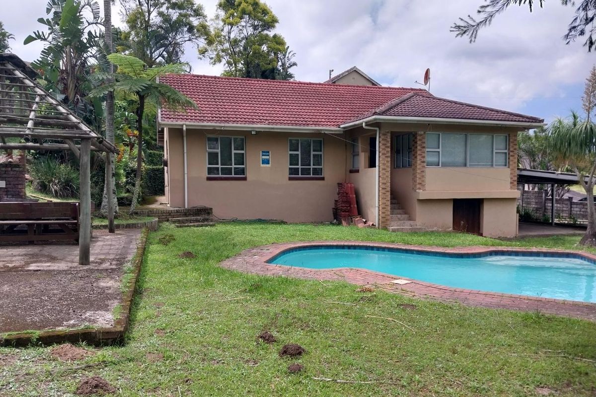 Rear view of the house featuring a swimming pool, brick paved surround, and a timber pergola structure set within a garden area.