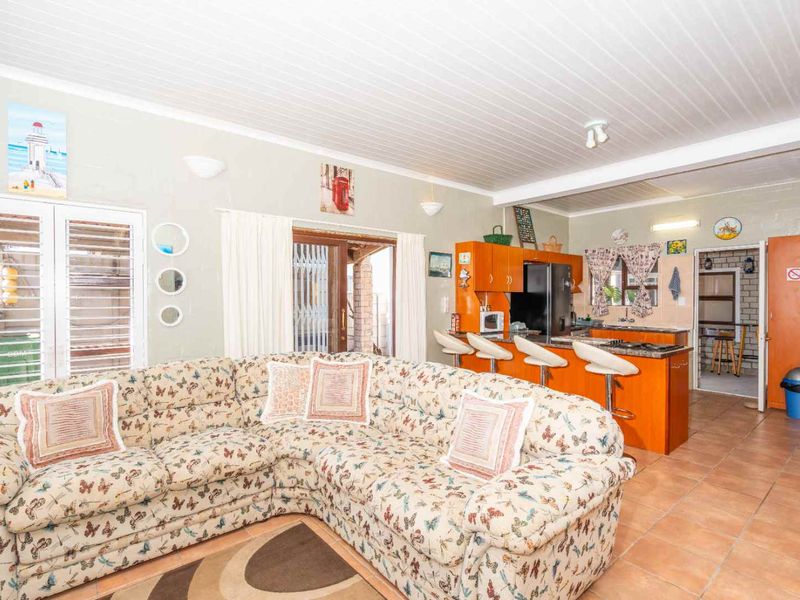 Open plan living area featuring a kitchen with island seating, tiled floors, and a tongue and groove ceiling, leading to an outdoor patio area.