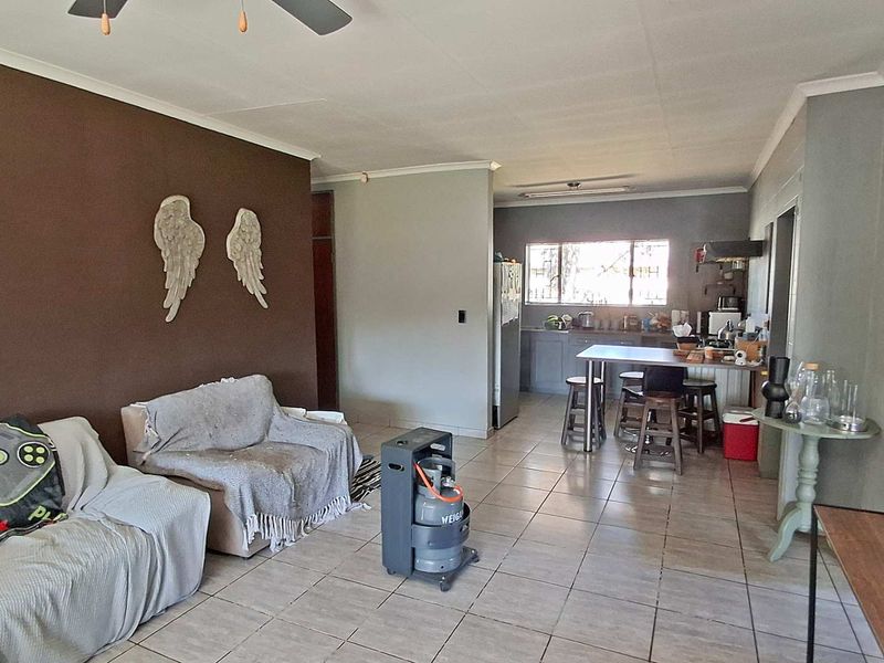 Open-plan living and kitchen area featuring tiled flooring, a central kitchen island, and a neutral color palette.