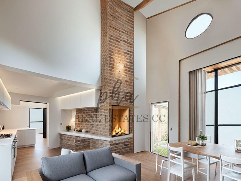 Spacious open-plan living area featuring a striking double-height exposed brick fireplace, modern kitchen with integrated appliances, and abundant natural light from large windows.