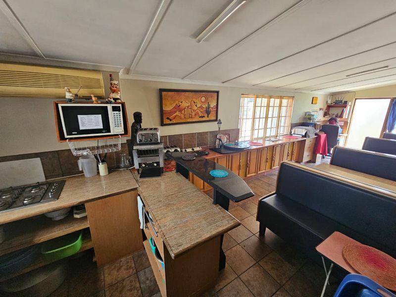 Open-plan kitchen and living area featuring granite countertops, built-in cabinetry, and tiled flooring, offering a functional layout with potential for modern updates.