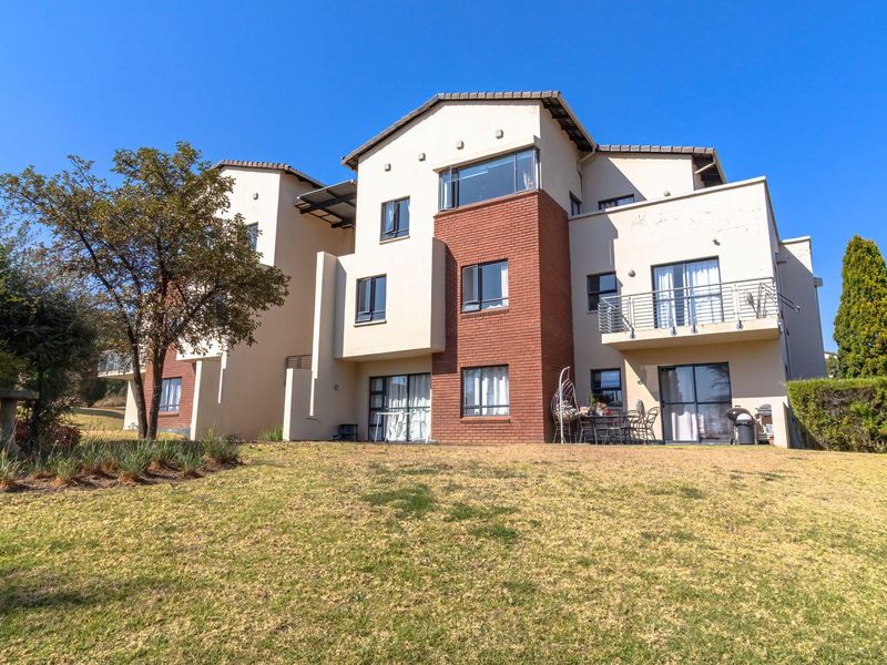 Rear view of a multi-story apartment building featuring brick and plaster finishes, balconies with metal railings, and sliding glass door access to the garden.