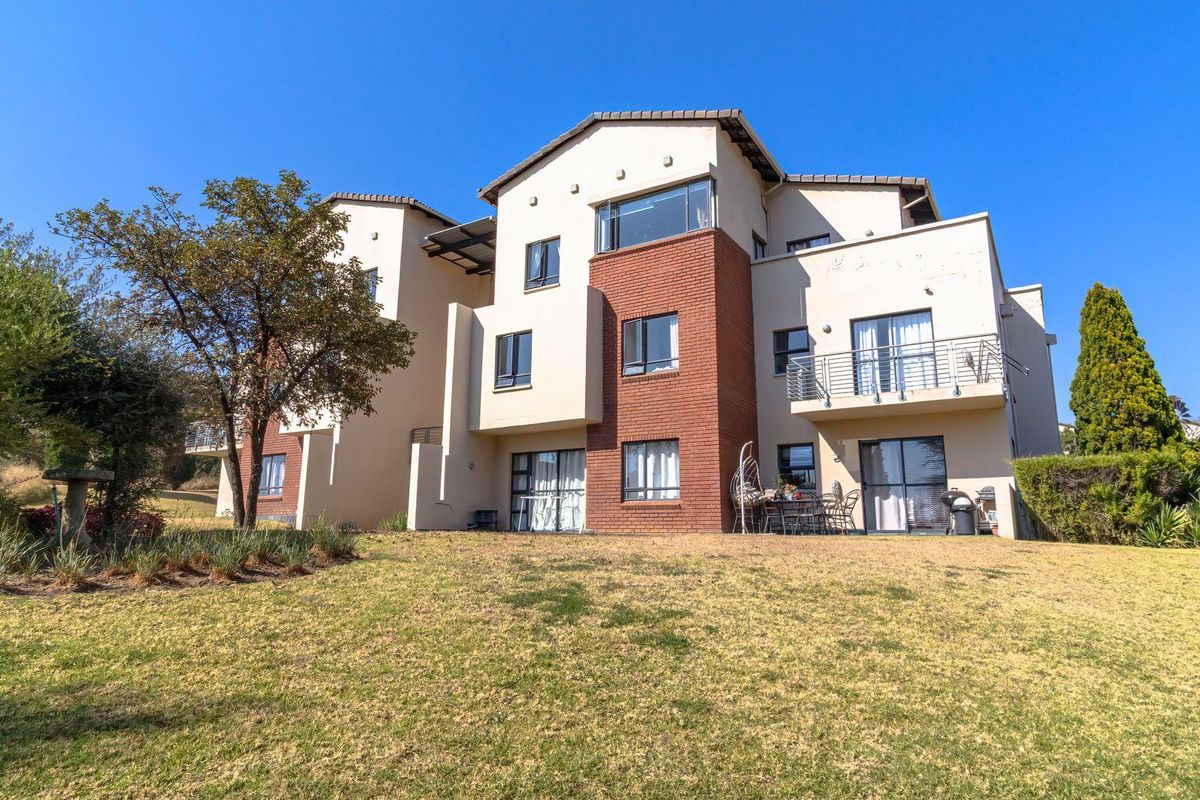 Rear view of a multi-story apartment building featuring brick and plaster finishes, balconies with metal railings, and sliding glass door access to the garden.