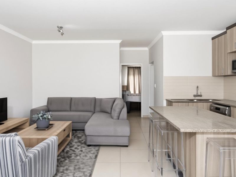 Modern open-plan living area featuring a well-appointed kitchen with granite countertops, integrated appliances, and neutral tiled flooring throughout.