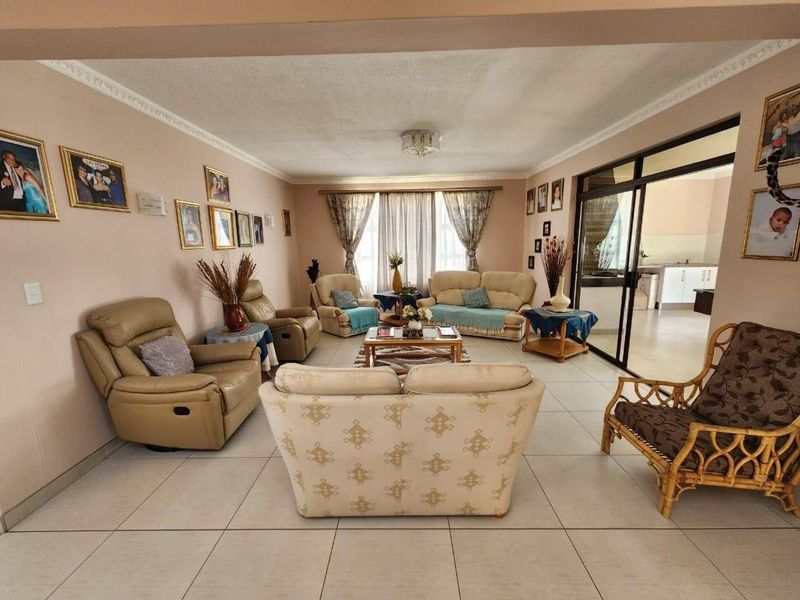 Spacious living room featuring neutral tiled flooring, decorative ceiling cornices, and a sliding glass door providing access to an adjacent area.