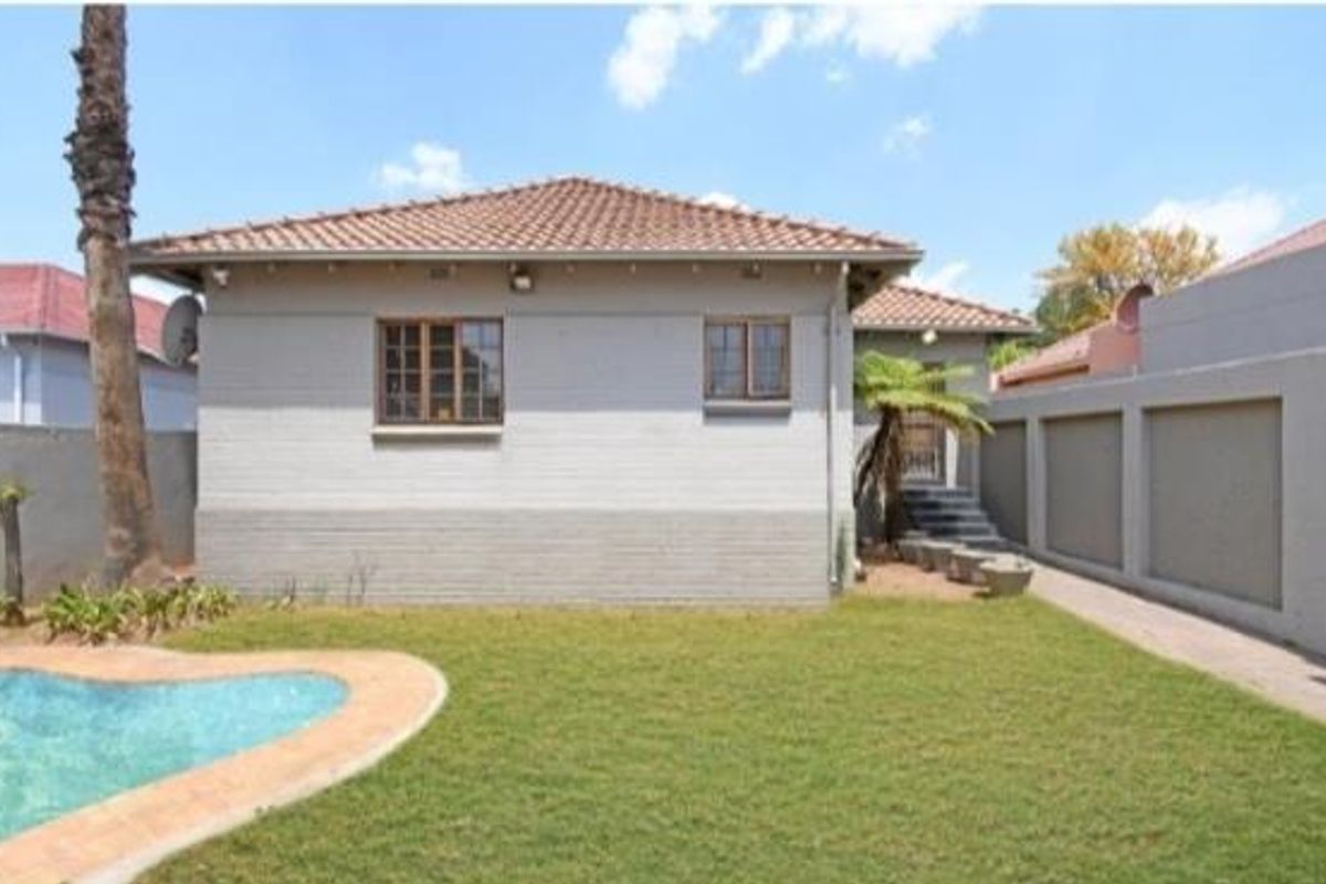 Rear view of the property featuring a swimming pool, landscaped lawn, and a paved walkway leading to the main structure.