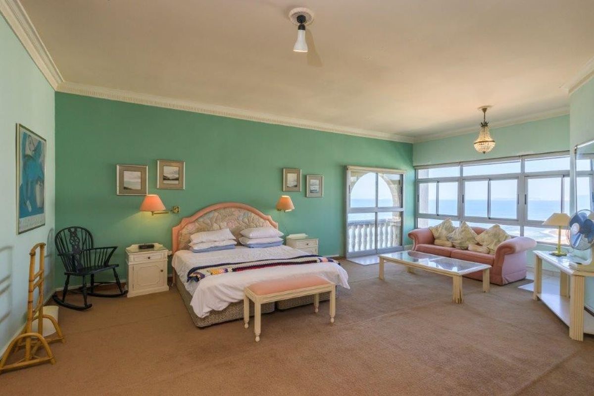 Spacious bedroom featuring large windows with ocean views, crown molding, and direct access to a private balcony.