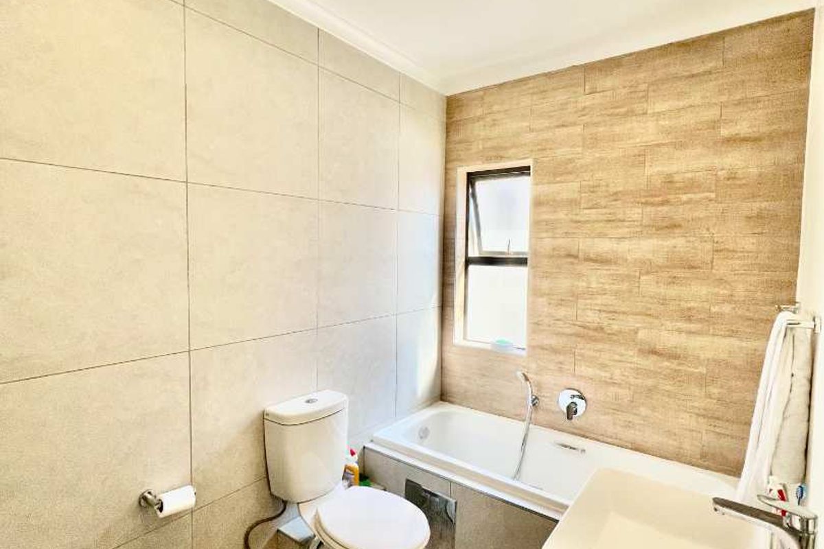 A modern bathroom featuring a built-in bathtub, a contemporary vessel sink vanity, and neutral floor-to-ceiling wall tiling.