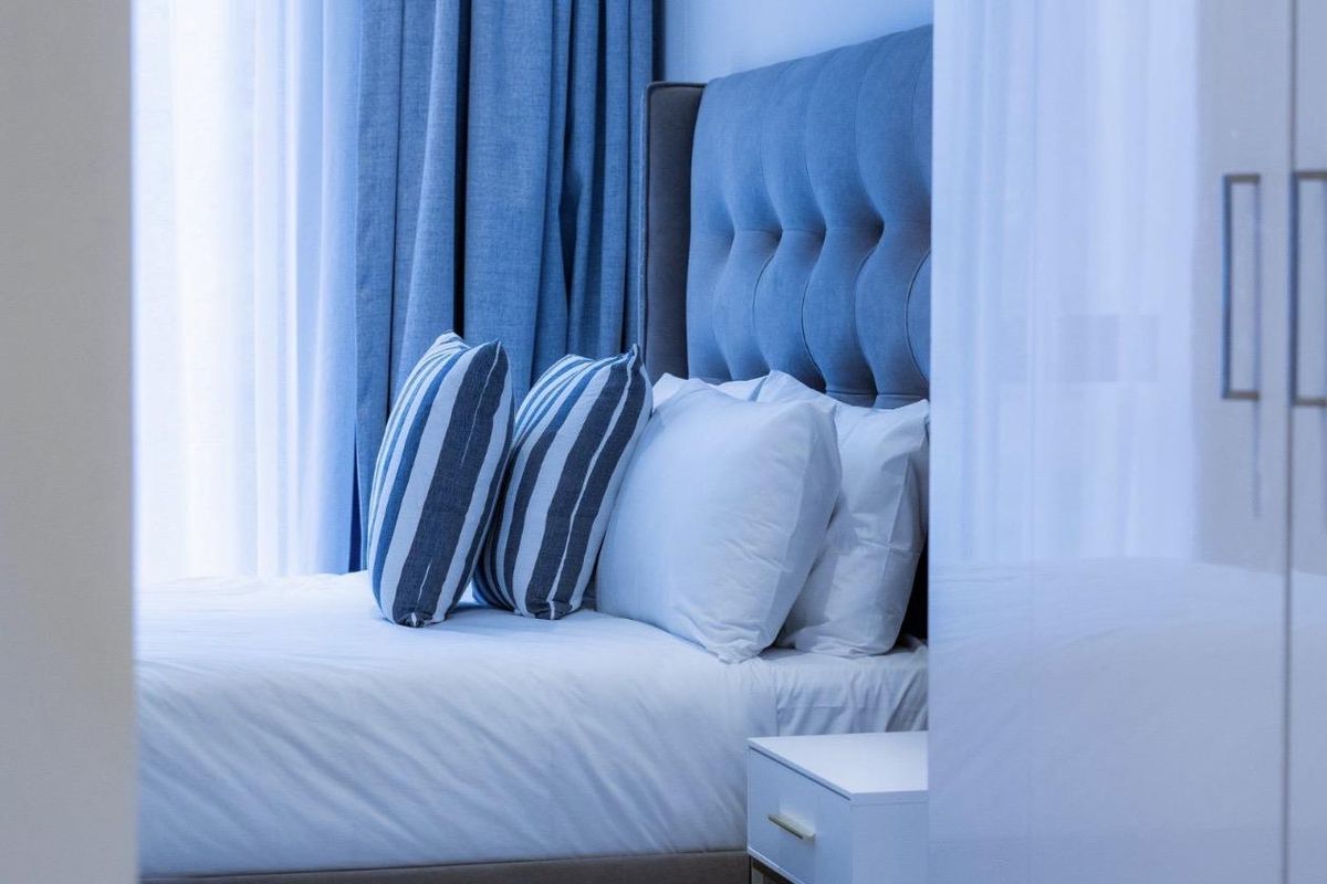 A well-maintained bedroom featuring a modern built-in wardrobe and a comfortable sleeping area with neutral finishes.
