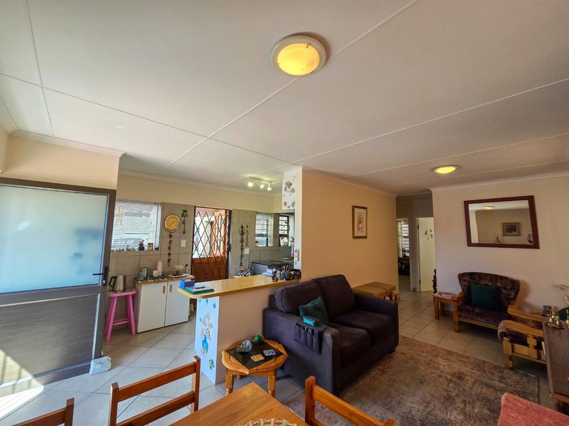 Open plan living and kitchen area featuring tiled flooring, a breakfast bar, and direct access to an exterior security gate.