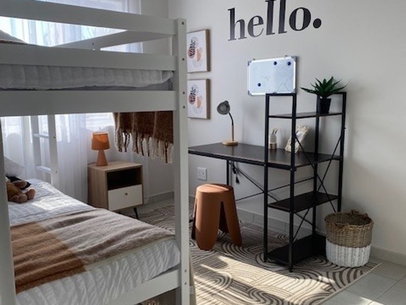 A well-lit bedroom featuring tiled flooring and a classic tongue and groove ceiling, providing a comfortable and functional living space.
