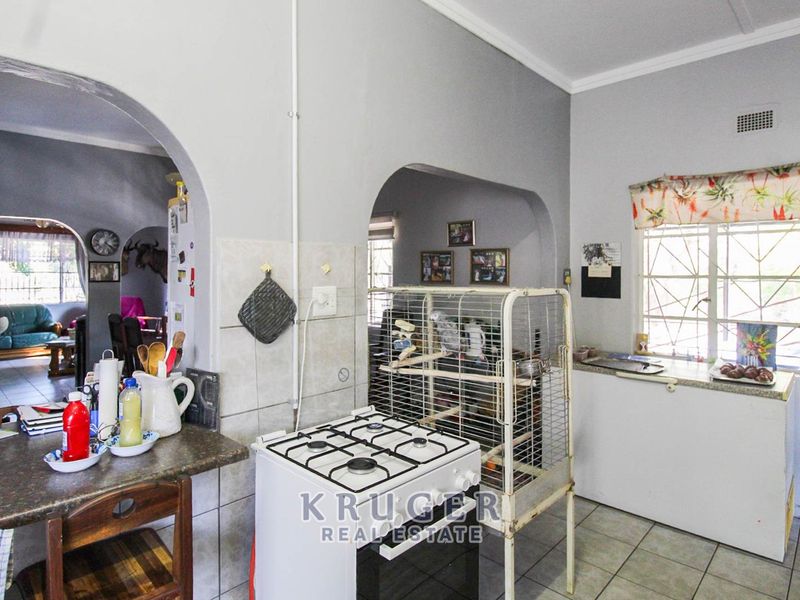 A functional kitchen featuring tiled flooring, a gas stove, and an open-plan layout with arched transitions to the adjacent living area.