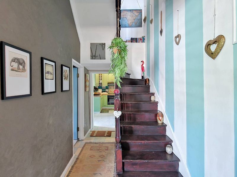 A characterful hallway featuring a dark timber staircase with a traditional balustrade, leading through to a kitchen area.