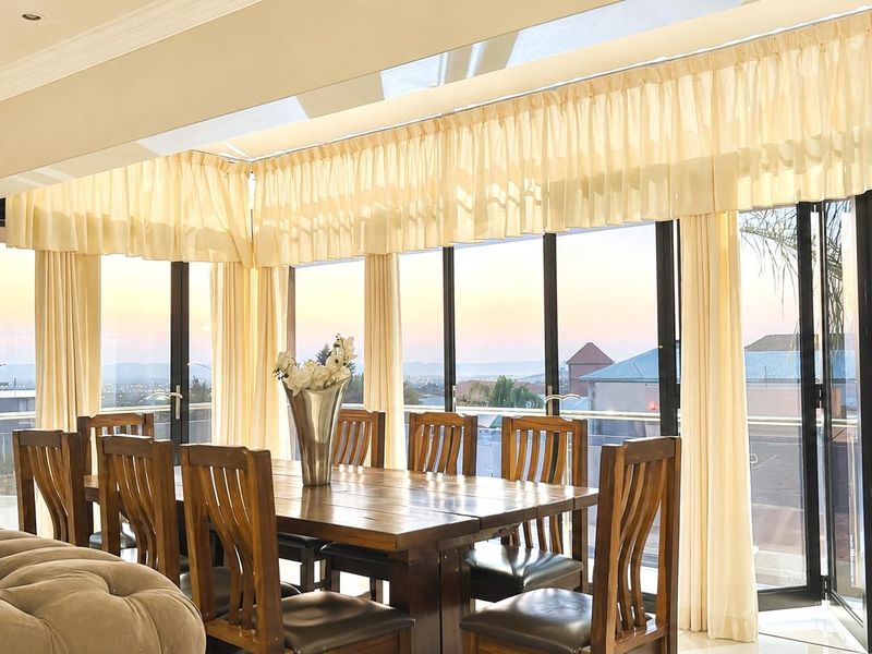 Bright dining area featuring large aluminium stacking doors, a skylight, and recessed downlights, offering expansive views and abundant natural light.