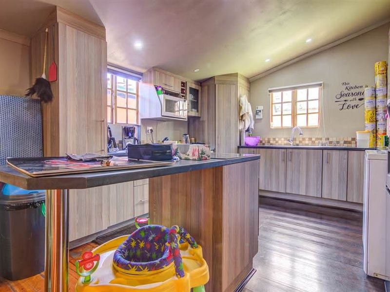 A functional kitchen featuring wood-look laminate cabinetry, a central island, built-in microwave, and ample counter space with a stainless steel sink.