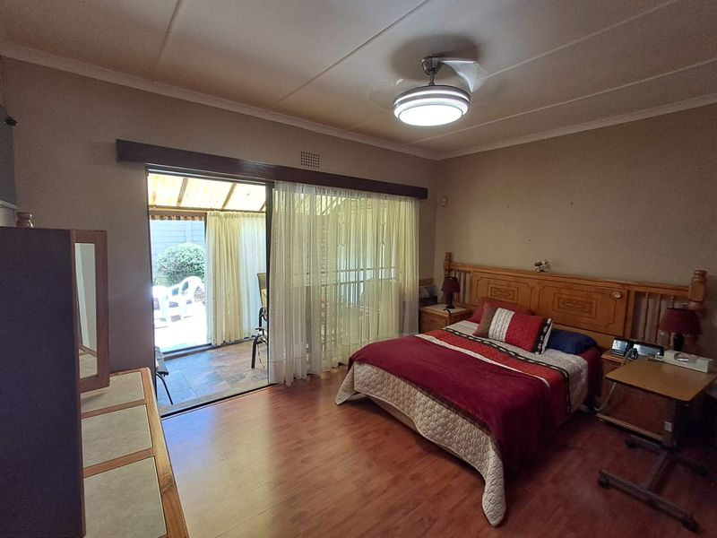 Spacious bedroom featuring laminate flooring, a ceiling fan, and a sliding glass door providing direct access to an outdoor patio area.