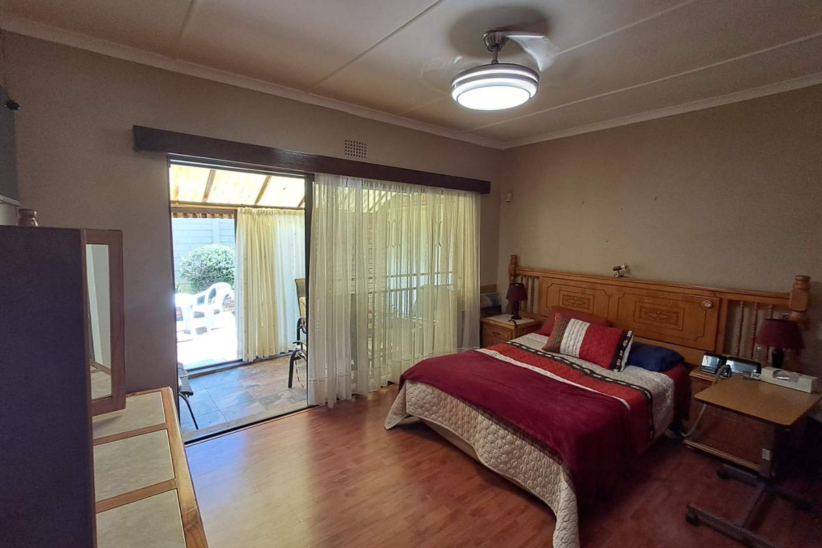 Spacious bedroom featuring laminate flooring, a ceiling fan, and a sliding glass door providing direct access to an outdoor patio area.
