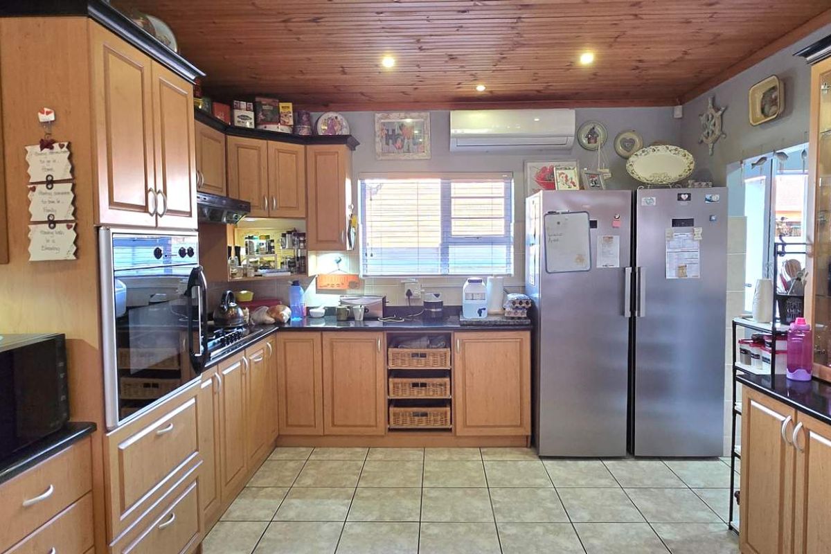 A functional kitchen featuring timber cabinetry, dark countertops, a built-in oven, extractor fan, and tiled flooring with a timber-paneled ceiling.