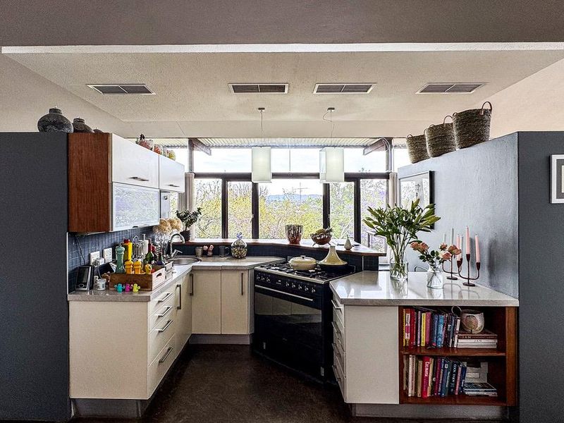 Modern kitchen featuring built-in cabinetry, stone countertops, a gas stove, and large windows providing natural light and scenic views.