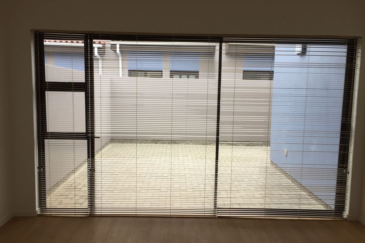 View from an interior room looking out through large sliding glass doors onto a paved courtyard area.
