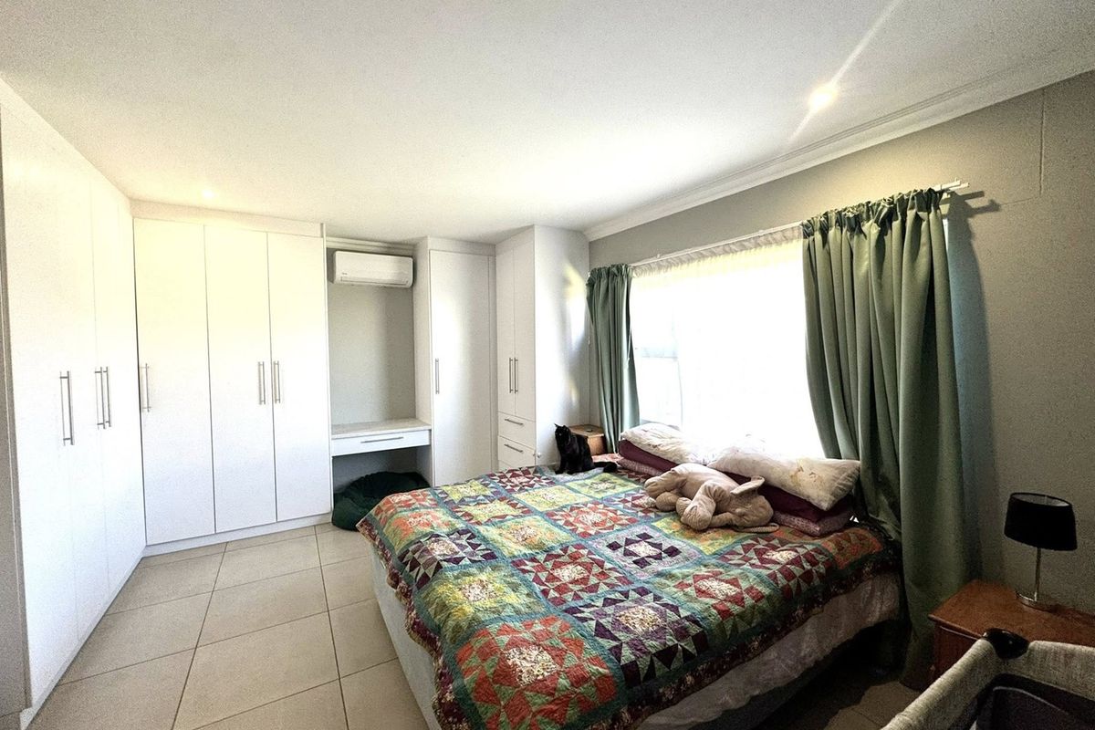 Spacious bedroom featuring extensive built-in cabinetry, tiled flooring, and a wall-mounted air conditioning unit.