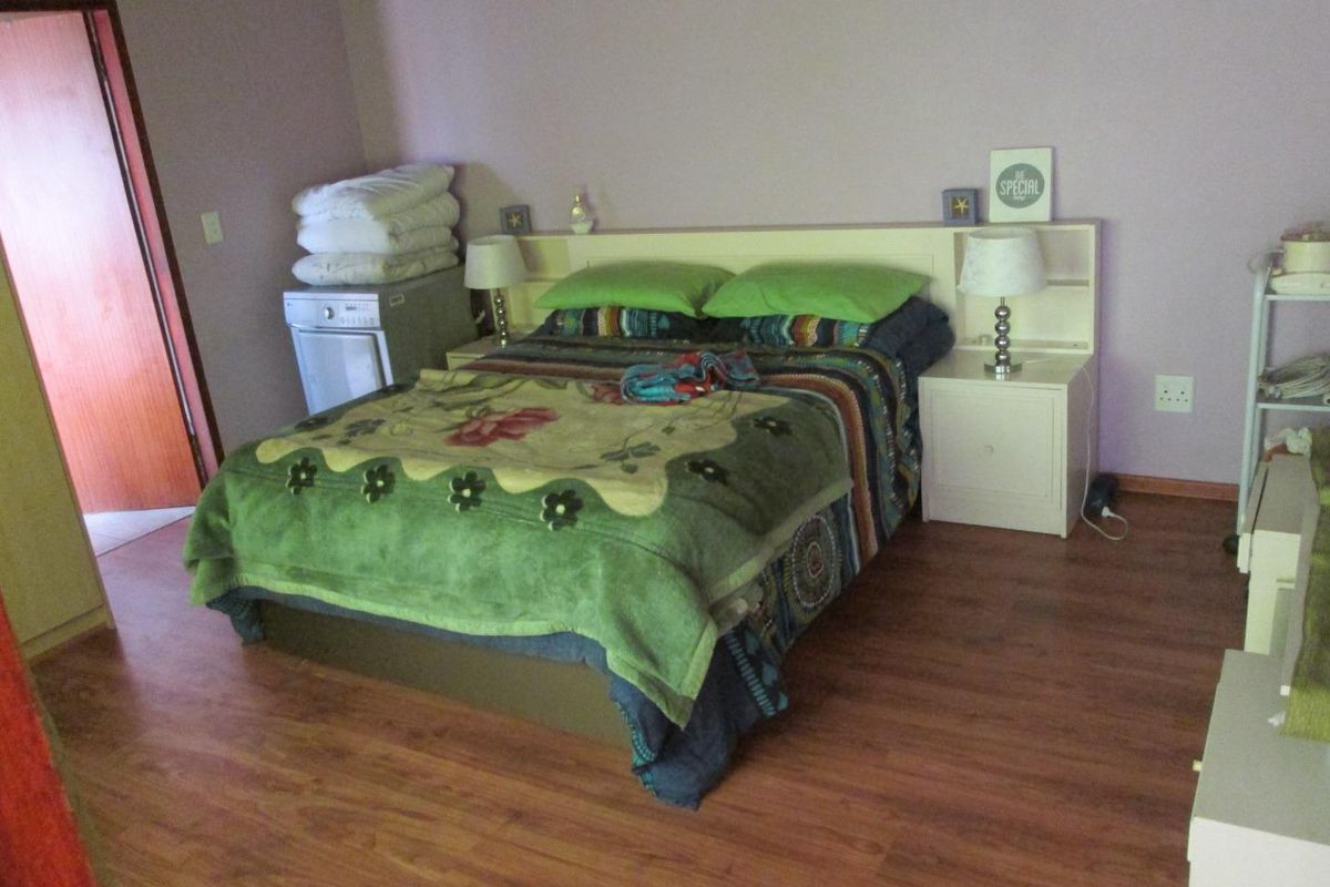 A bedroom featuring laminate flooring and a built-in headboard with integrated bedside storage.