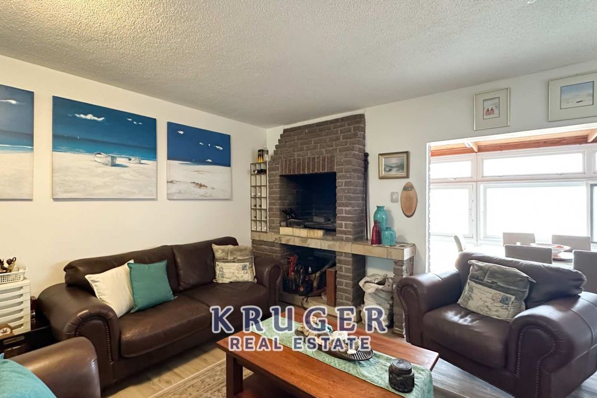 Cozy living room featuring a traditional brick fireplace and laminate flooring, with direct access to an adjoining sunroom area.