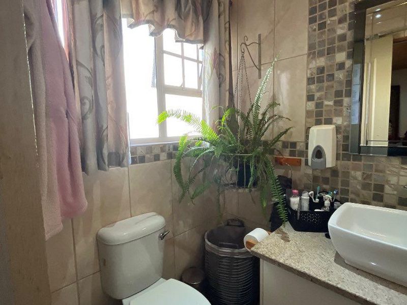A compact bathroom featuring a vessel sink on a granite vanity, mosaic tile accents, and a timber-clad ceiling.