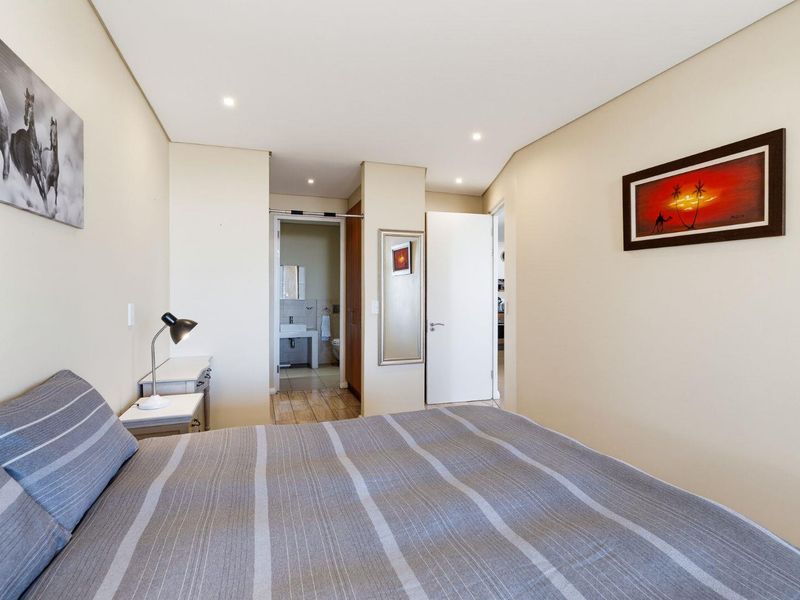 A well-maintained bedroom featuring recessed downlighting, neutral wall finishes, and direct access to an en-suite bathroom with built-in storage.