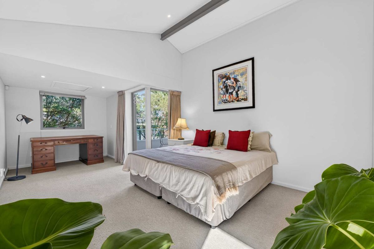 Spacious bedroom featuring a vaulted ceiling with exposed beam, neutral carpeting, and sliding glass door access to an outdoor area.