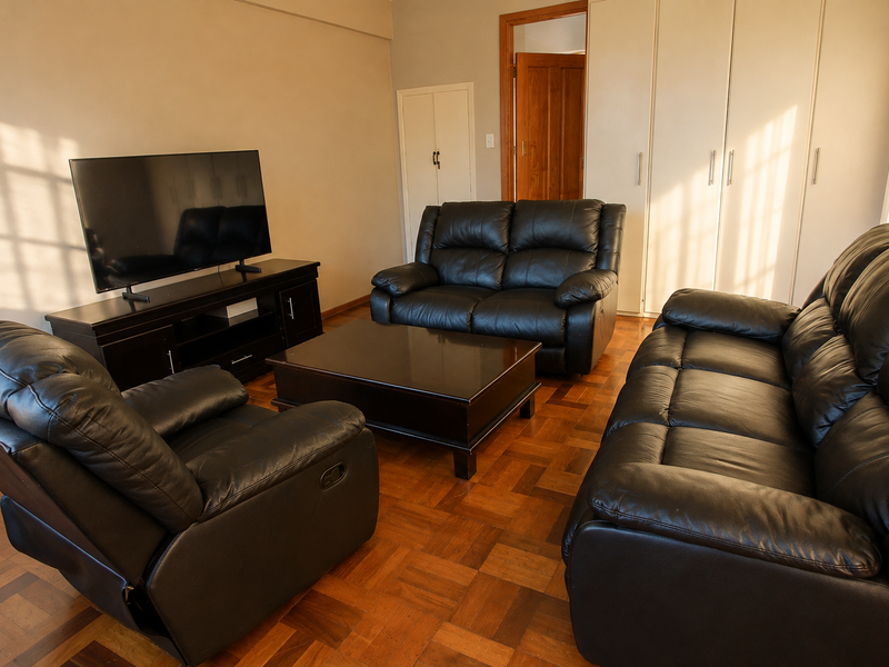 A living room featuring classic parquet flooring and extensive built-in storage cupboards, providing a functional and traditional living space.