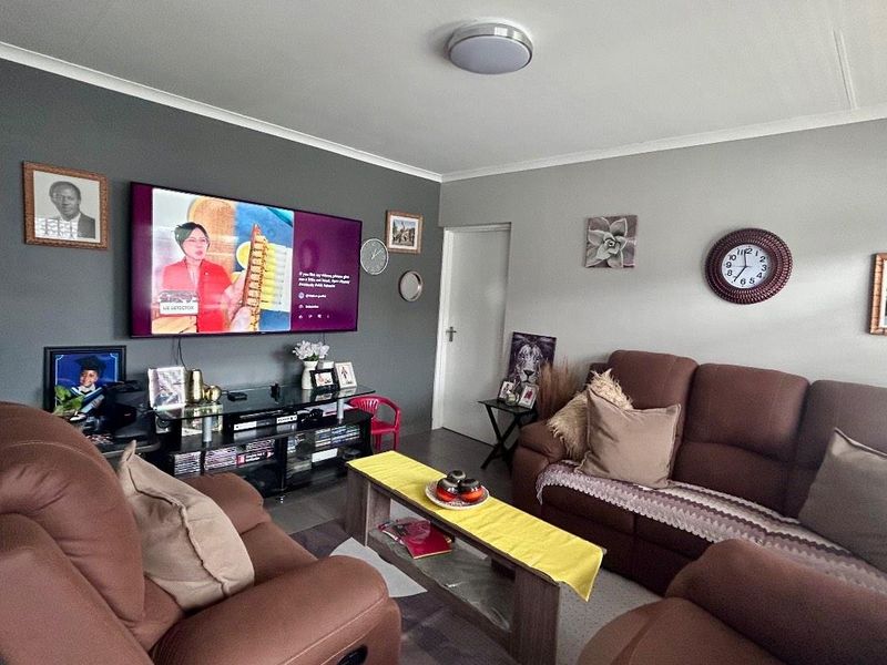 A comfortable living room featuring a dark accent wall, neutral wall tones, and a central flush mount ceiling light.